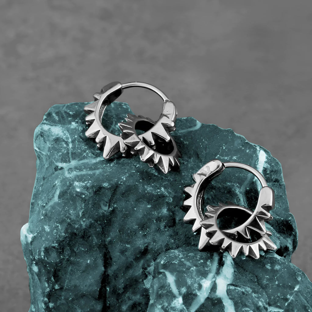 Pair of polished steel-coloured stainless steel round hoop earrings on a plain background.
