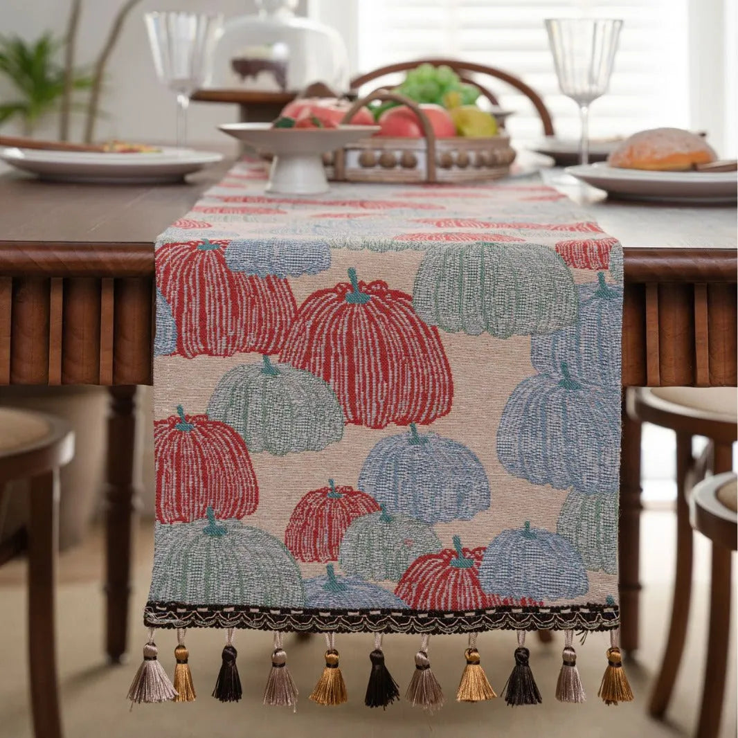 Beige jacquard table runner with floral pattern and long tassels draped over a wooden wedding table.