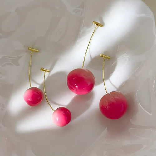 A pair of glossy peach-shaped acrylic earrings on copper posts, shown in small and large size options.