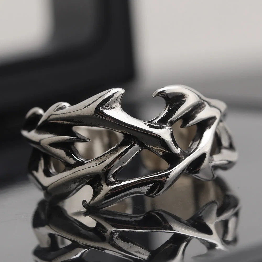 Copper geometric ring with thorn and flower design on a finger, showing adjustable opening.