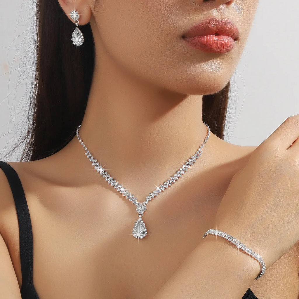 Women's blue claw chain necklace and drop rhinestone earrings set on white background.