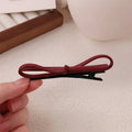 Handmade wine red leather bow barrette on a metal hair clip, showing the 5.5cm wide bow shape.