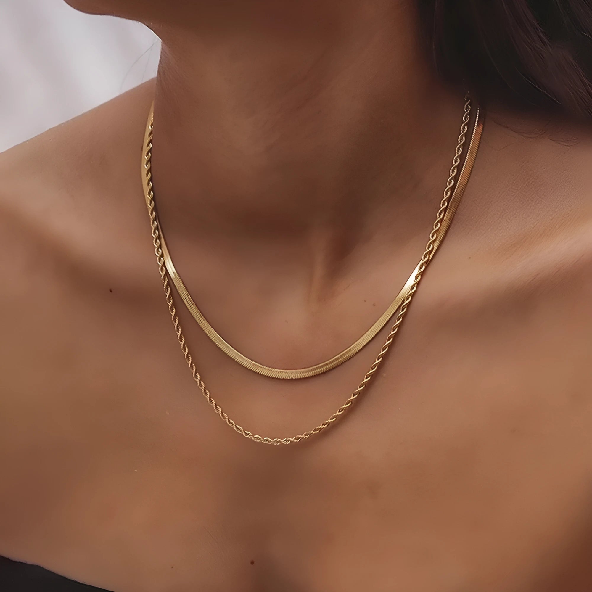 Women's silver geometric twist pendant necklace on adjustable snake bone chain against grey background.
