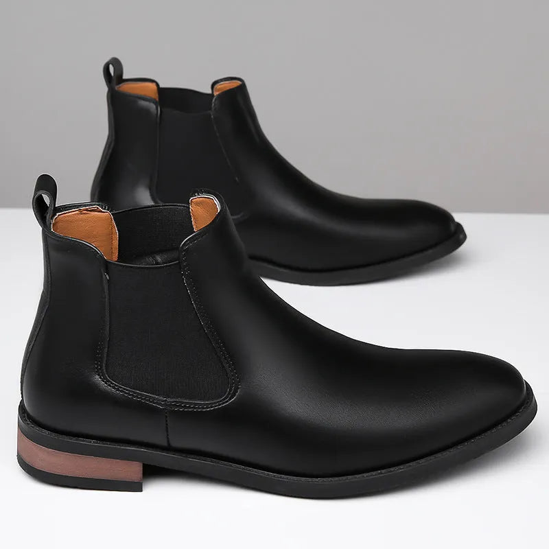 Men's black pointed-toe Chelsea boots with a low heel and rubber sole on a white background.