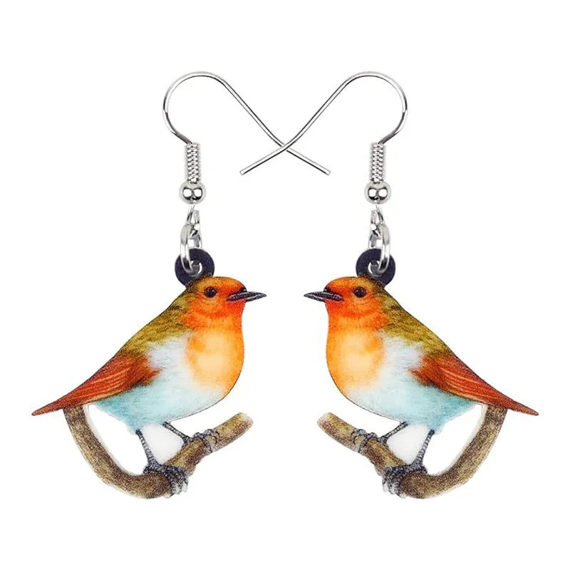 A pair of blue, white, and black acrylic drop earrings featuring a detailed Blue Tit bird and geometric snake patterns on a white background.