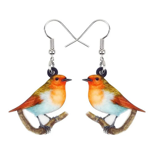 A pair of blue, white, and black acrylic drop earrings featuring a detailed Blue Tit bird and geometric snake patterns on a white background.