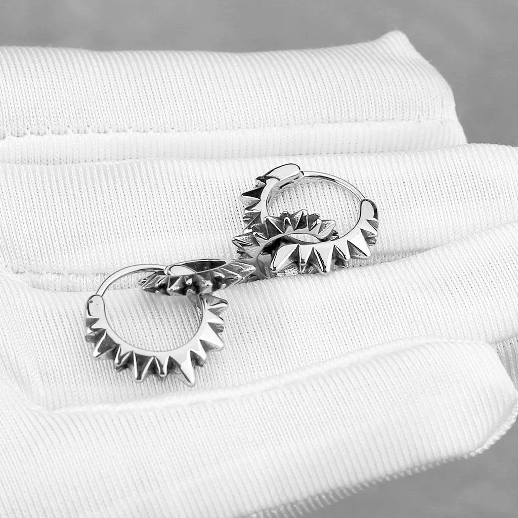 Pair of polished steel-coloured stainless steel round hoop earrings on a plain background.