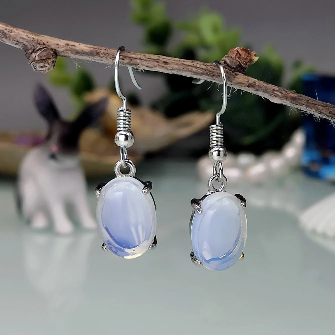 Pair of retro-style drop earrings with a moonlight opal colour and cross detail on an alloy base.