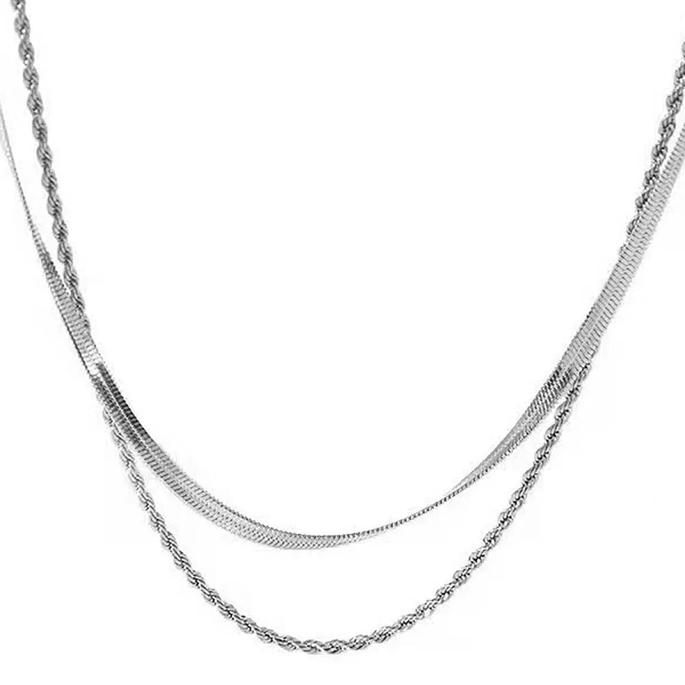 Women's silver geometric twist pendant necklace on adjustable snake bone chain against grey background.