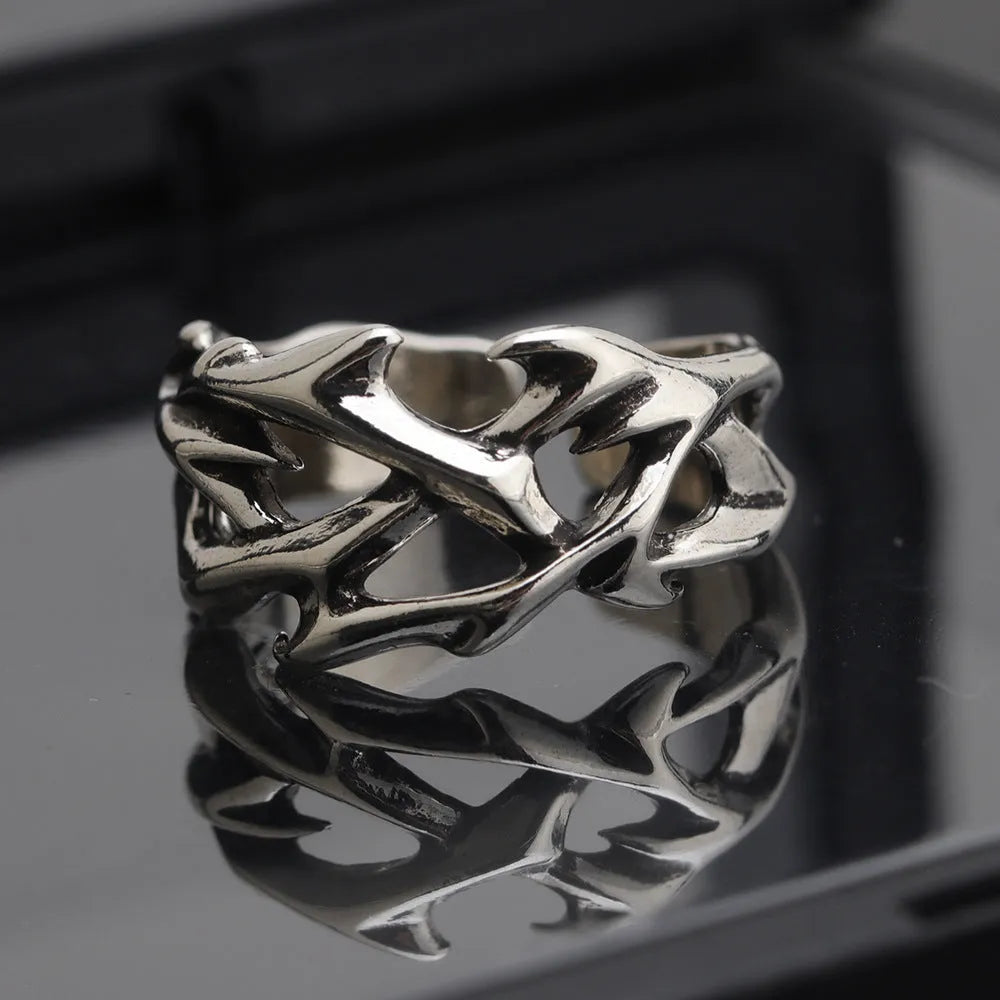 Copper geometric ring with thorn and flower design on a finger, showing adjustable opening.