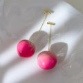 A pair of glossy peach-shaped acrylic earrings on copper posts, shown in small and large size options.