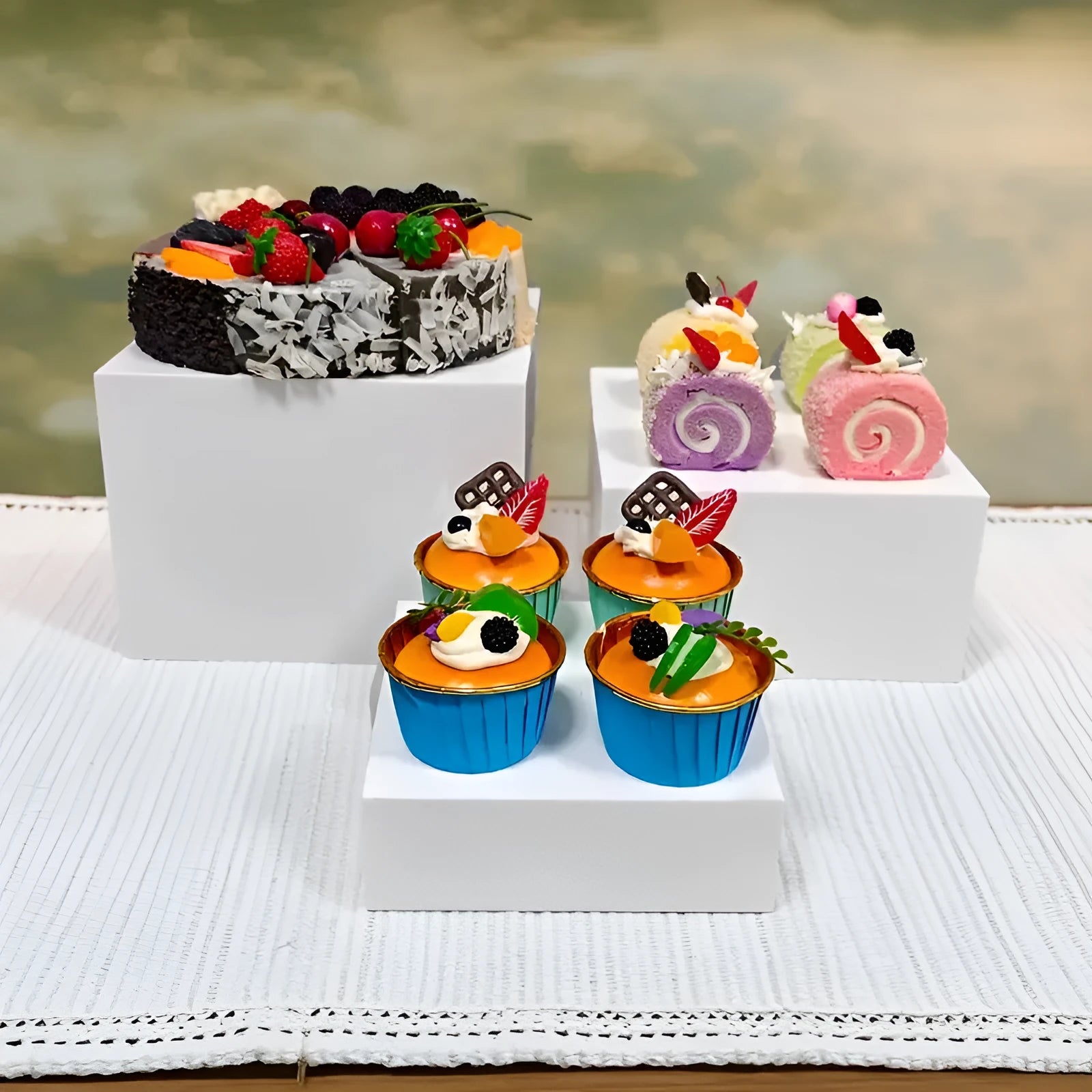 White plastic cube-shaped dessert display stand with multiple tiers for cupcakes and pastries.