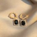 A pair of black geometric quadrilateral earrings with zircon stones on copper settings, shown against a plain background.