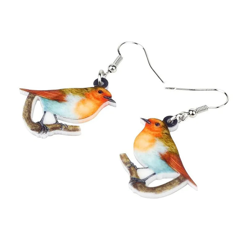 A pair of blue, white, and black acrylic drop earrings featuring a detailed Blue Tit bird and geometric snake patterns on a white background.