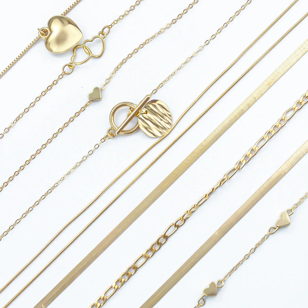 Set of ten gold-coloured women's necklaces with snake bone chains and alloy pendants on a white background.