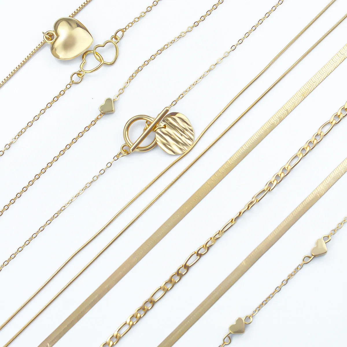 Set of ten gold-coloured women's necklaces with snake bone chains and alloy pendants on a white background.