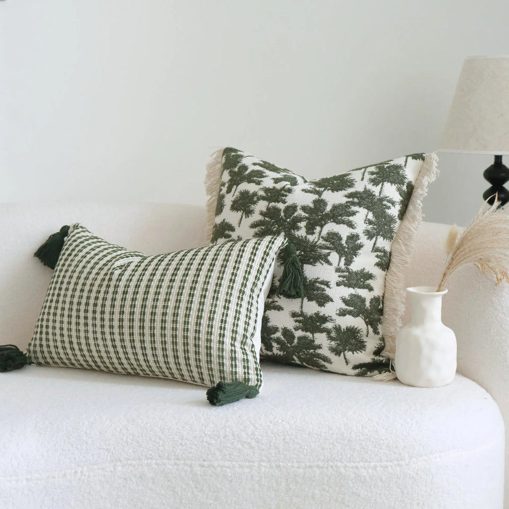 Green cotton and linen hotel pillow with botanical pattern and tassel trim on a bed display.