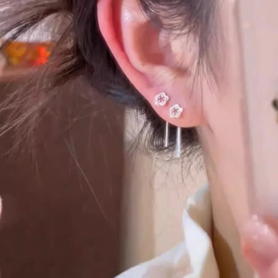 A pair of silver-coloured hollow flower stud earrings with petal details on sterling silver posts.