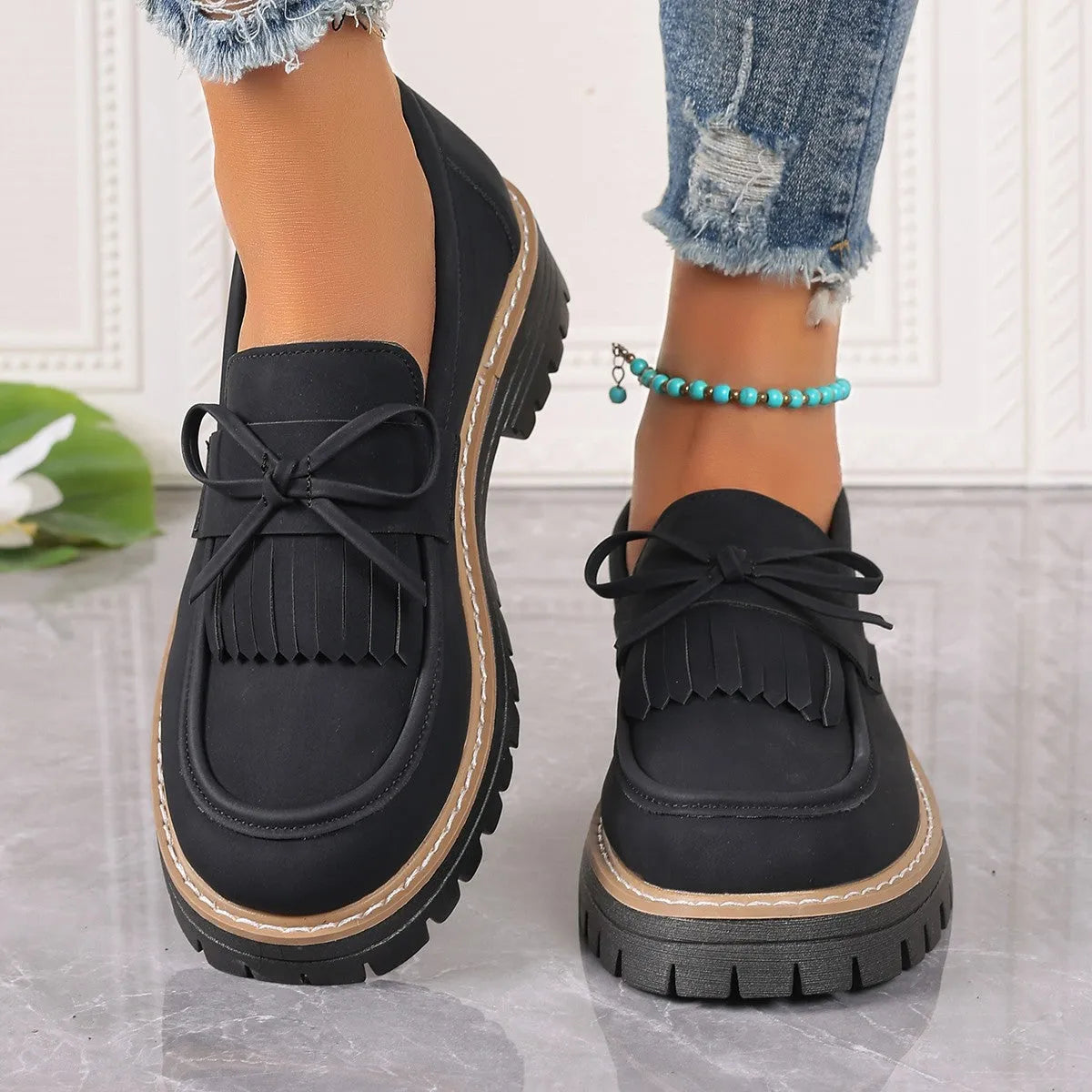 Women's plus size black loafers with tassel detail and a chunky flat rubber sole.