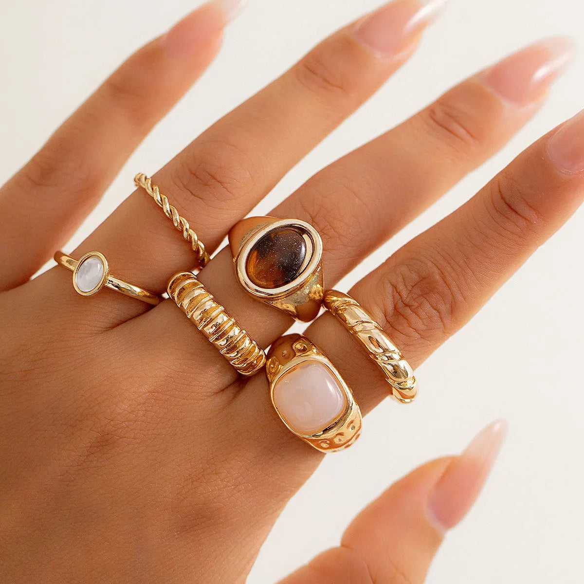 Six geometric irregular shaped alloy rings in light gold electroplated finish displayed together