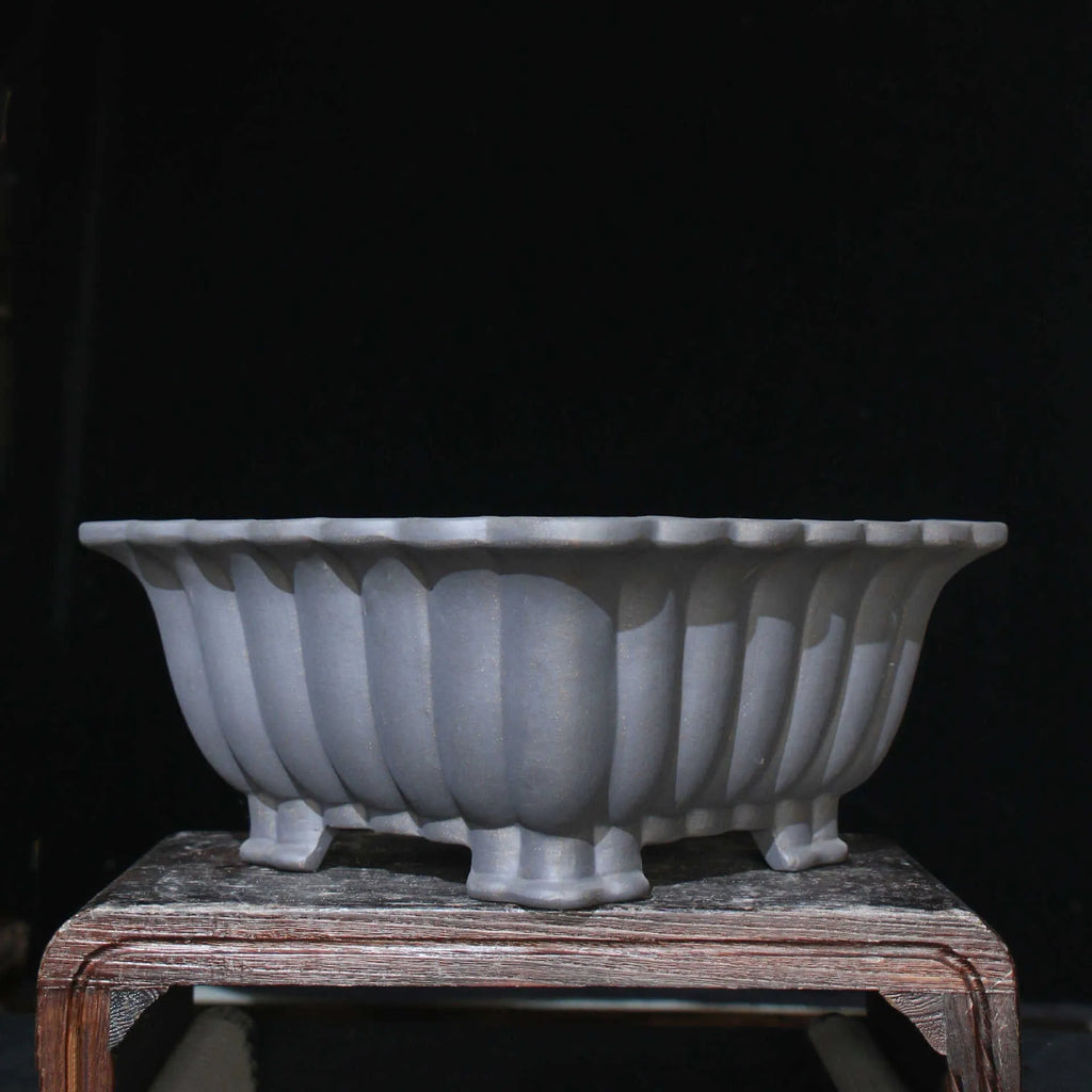 Square purple sand ceramic bonsai pot with du xiliang glaze on a desktop.