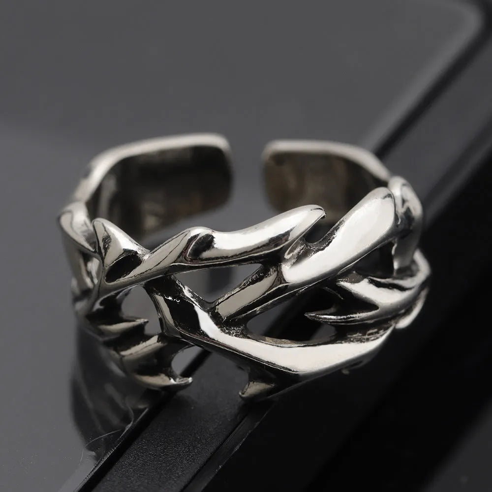 Copper geometric ring with thorn and flower design on a finger, showing adjustable opening.