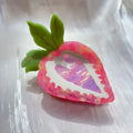 Handmade red and pink strawberry hairpin for girls on a white background.