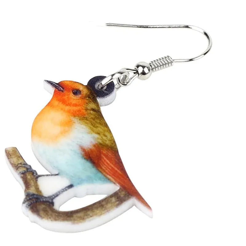 A pair of blue, white, and black acrylic drop earrings featuring a detailed Blue Tit bird and geometric snake patterns on a white background.