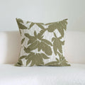 Green striped and botanical pattern decorative pillow with tassels on a bed.