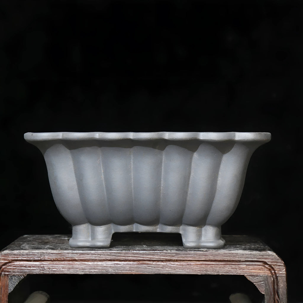 Square purple sand ceramic bonsai pot with du xiliang glaze on a desktop.