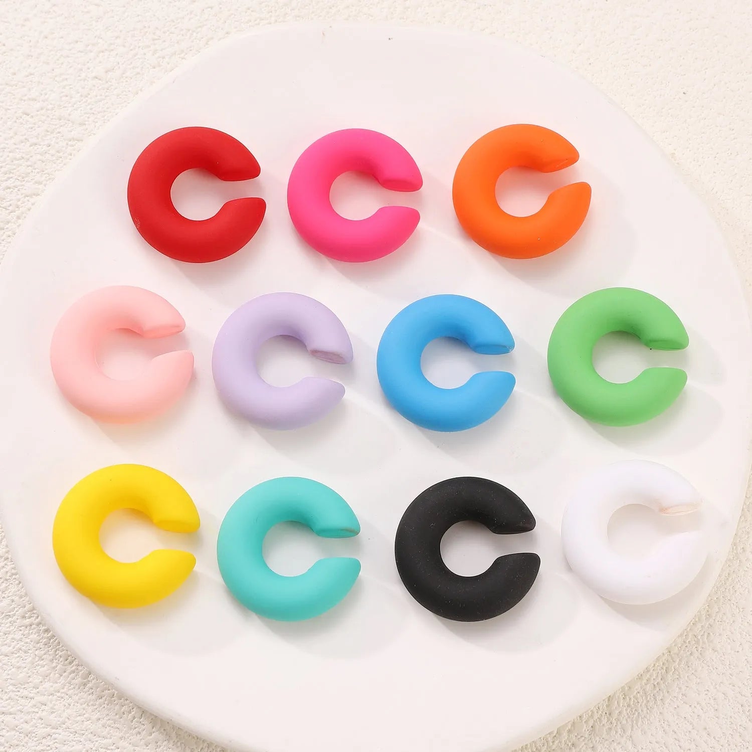 Round C-shaped clip-on earring with a matte coarse surface in a selection of candy colours.