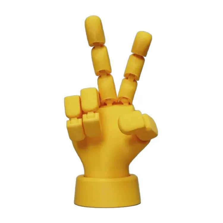 Yellow PLA movable joint hand prop ornament on a flat surface, showing articulated fingers.