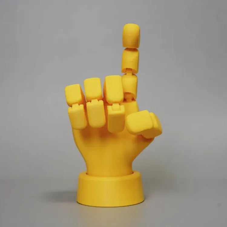 Yellow PLA movable joint hand prop ornament on a flat surface, showing articulated fingers.