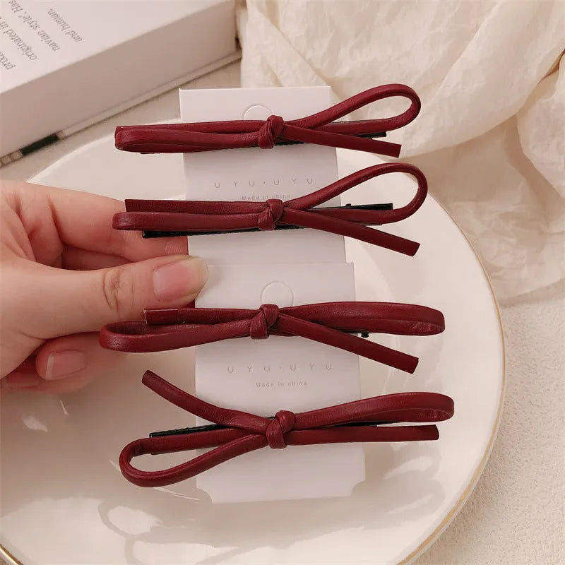 Handmade wine red leather bow barrette on a metal hair clip, showing the 5.5cm wide bow shape.