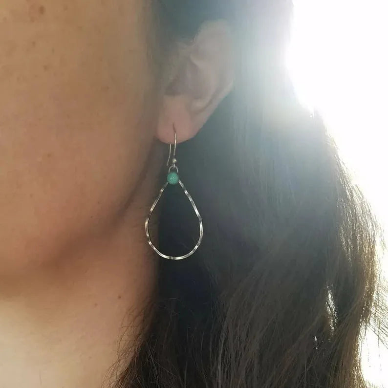 A pair of antique silver geometric circle earrings with a turquoise blue centre, showing bohemian vintage style.