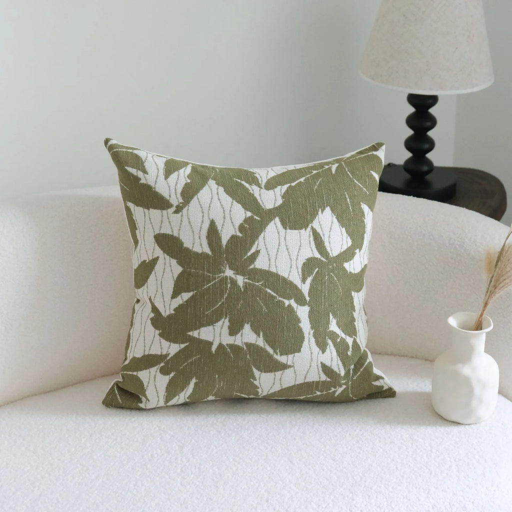 Green cotton and linen hotel pillow with botanical pattern and tassel trim on a bed display.