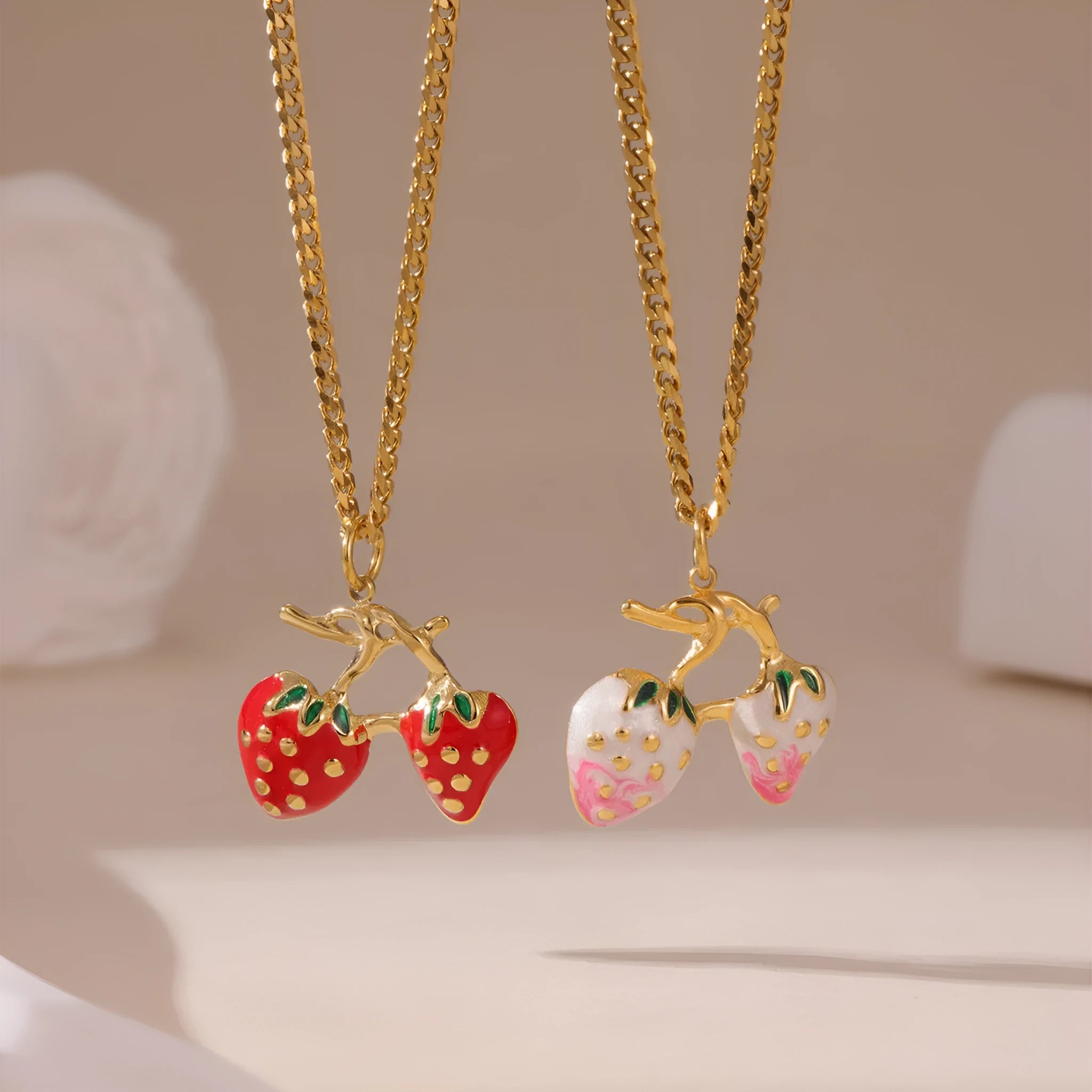 Close-up of a women's stainless steel necklace with a small red strawberry fruit pendant on a silver chain.