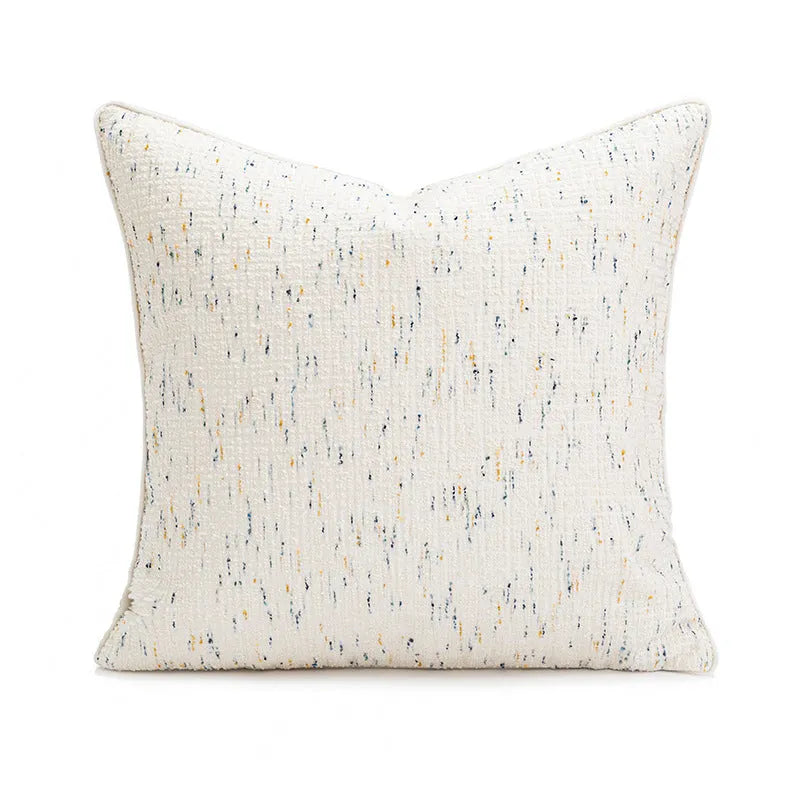 A square solid-colour cushion pillow on a sofa, showing its plain edge detail.