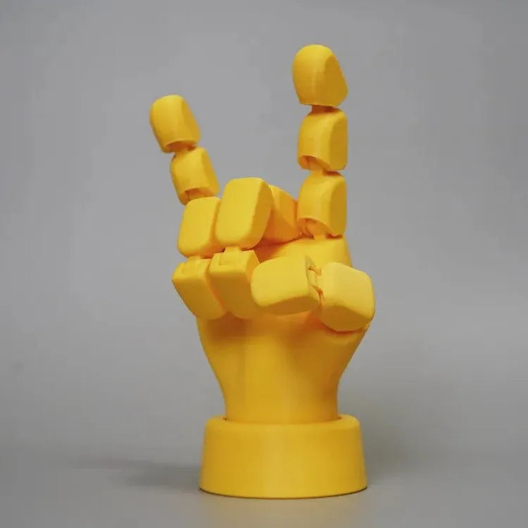 Yellow PLA movable joint hand prop ornament on a flat surface, showing articulated fingers.