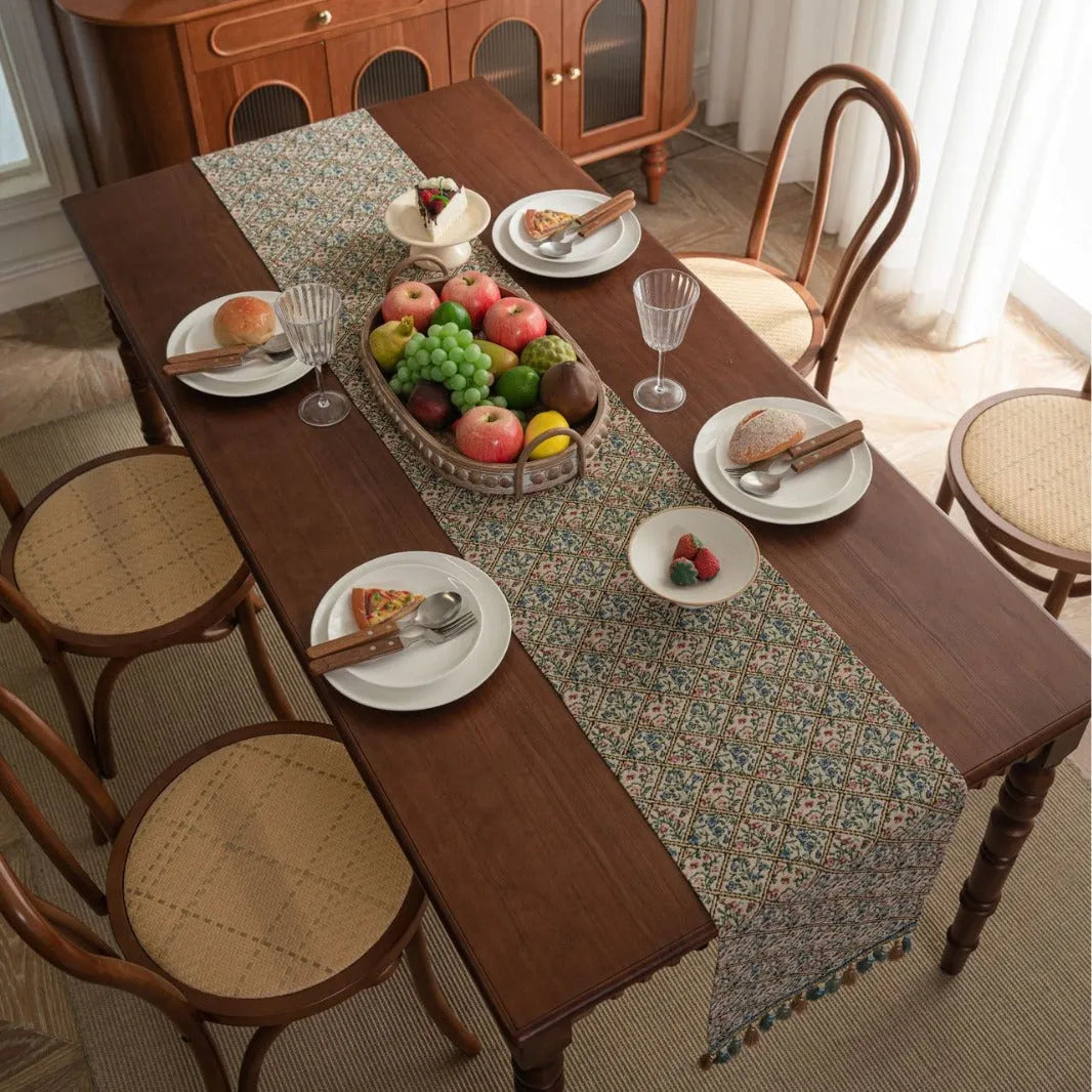 Nordic striped jacquard table runner with tassel on a dark wooden dining table.