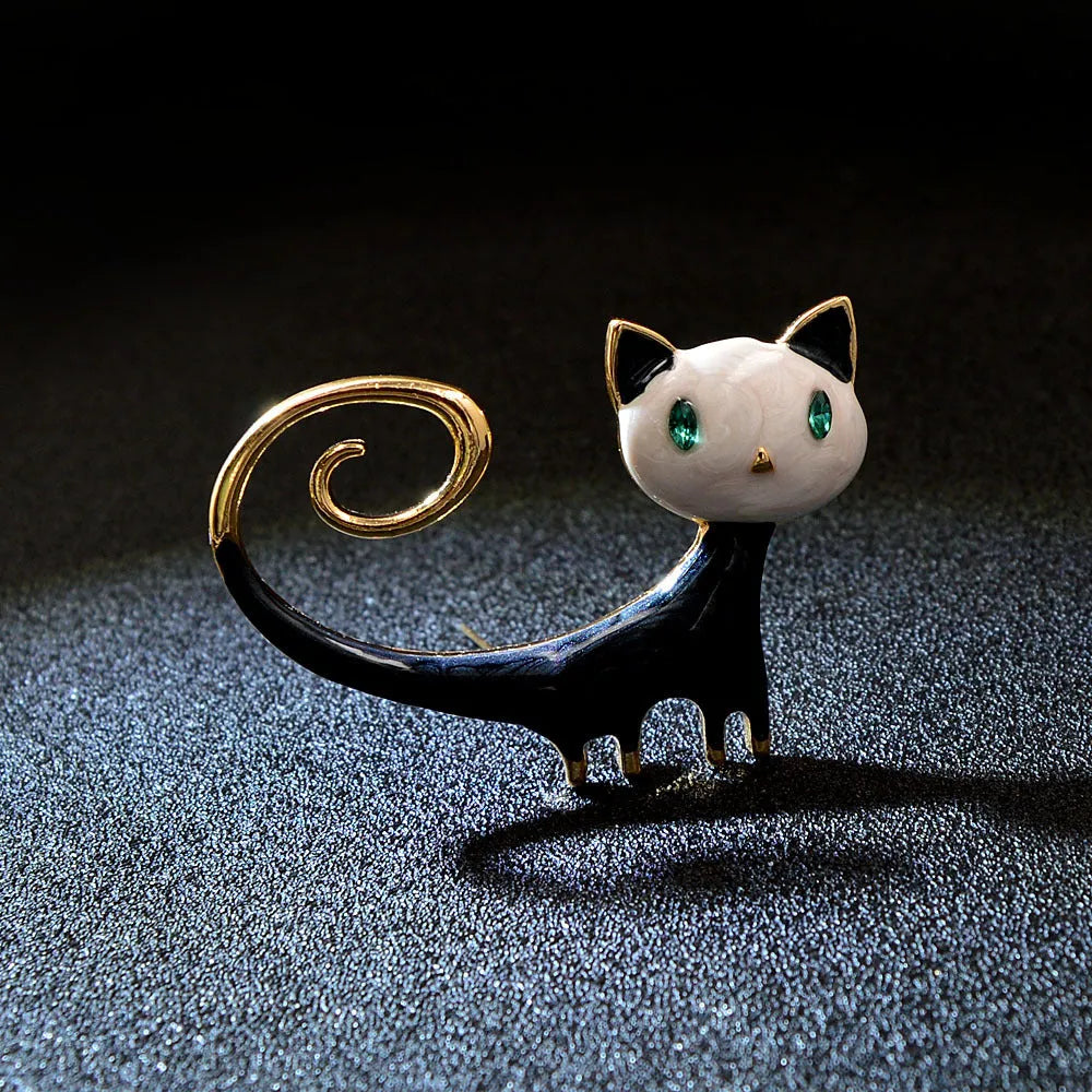 Orange and white alloy cat brooch with painted tail detail and pin fastener.