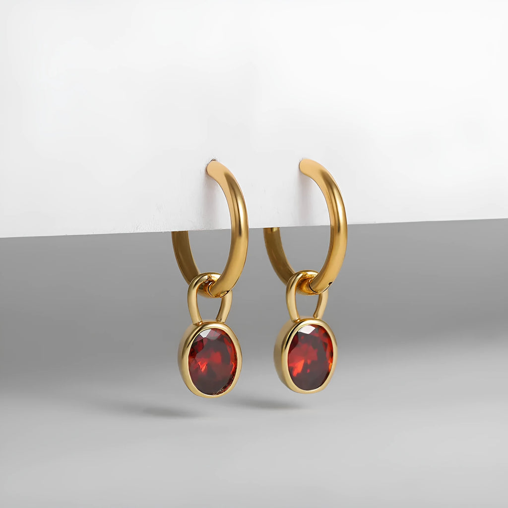Close-up of women's retro-style copper earrings featuring a single oval-cut zircon stone in an emerald green colour.