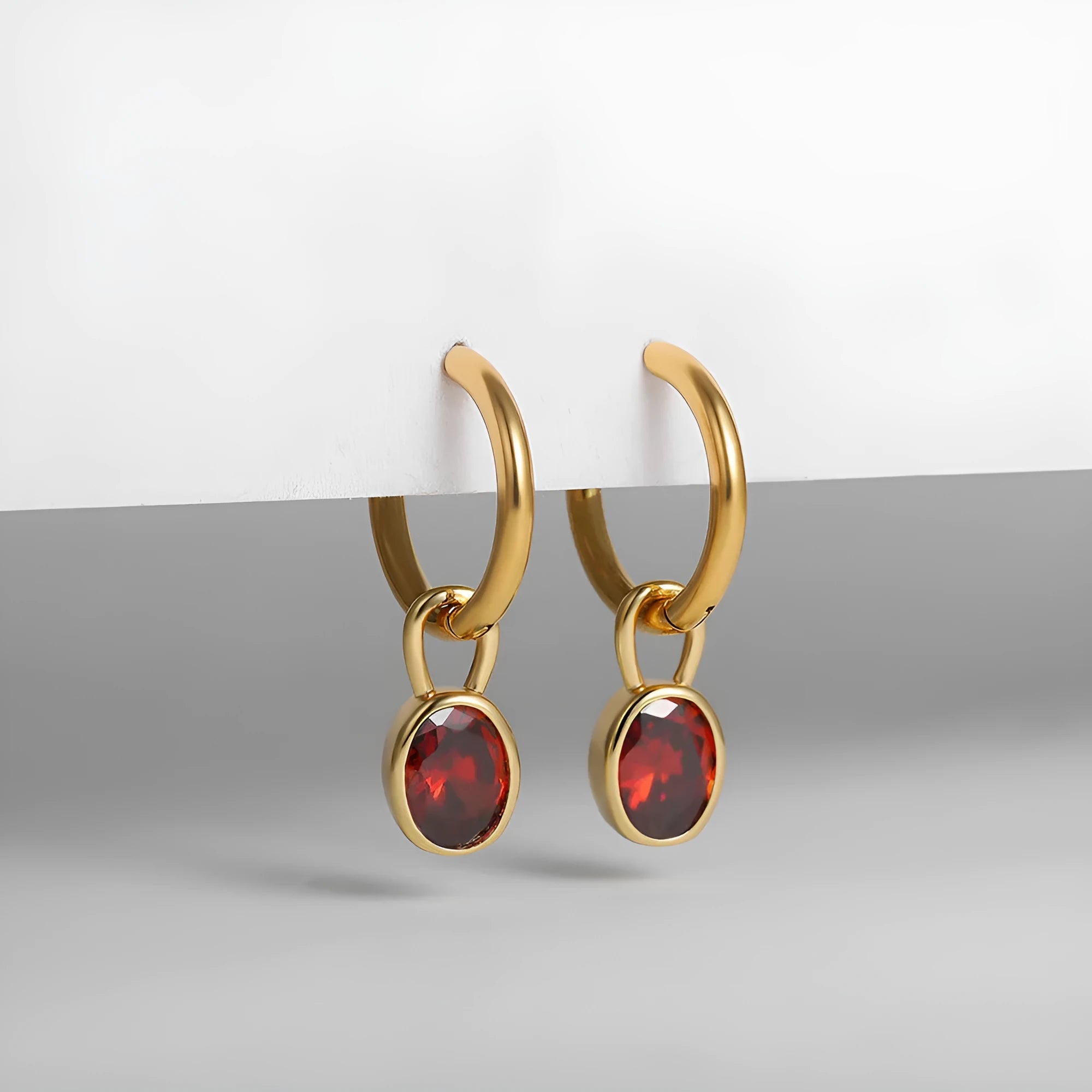Close-up of women's retro-style copper earrings featuring a single oval-cut zircon stone in an emerald green colour.