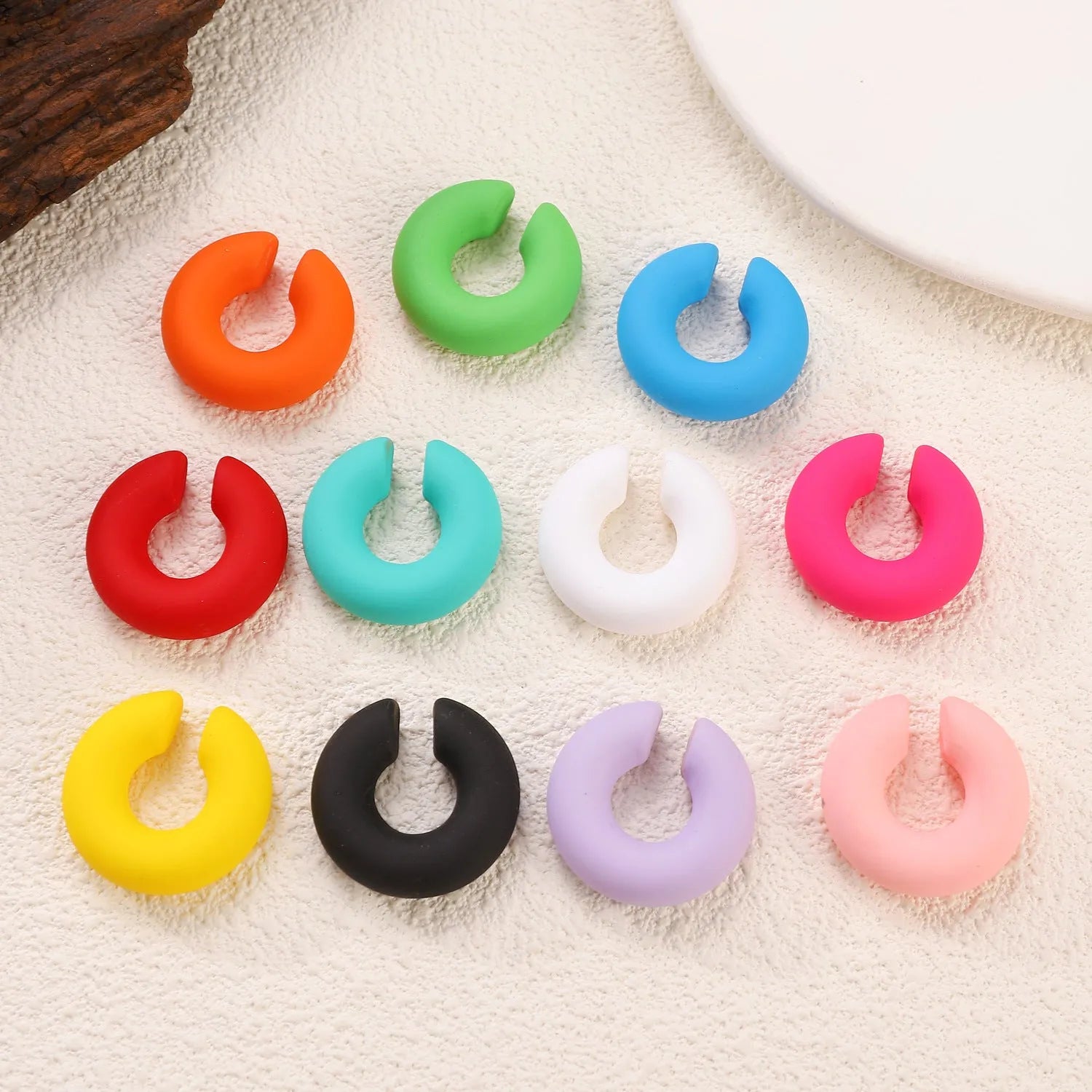 Round C-shaped clip-on earring with a matte coarse surface in a selection of candy colours.