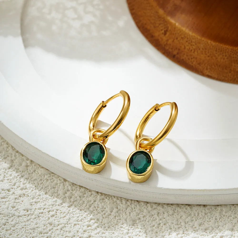 Close-up of women's retro-style copper earrings featuring a single oval-cut zircon stone in an emerald green colour.