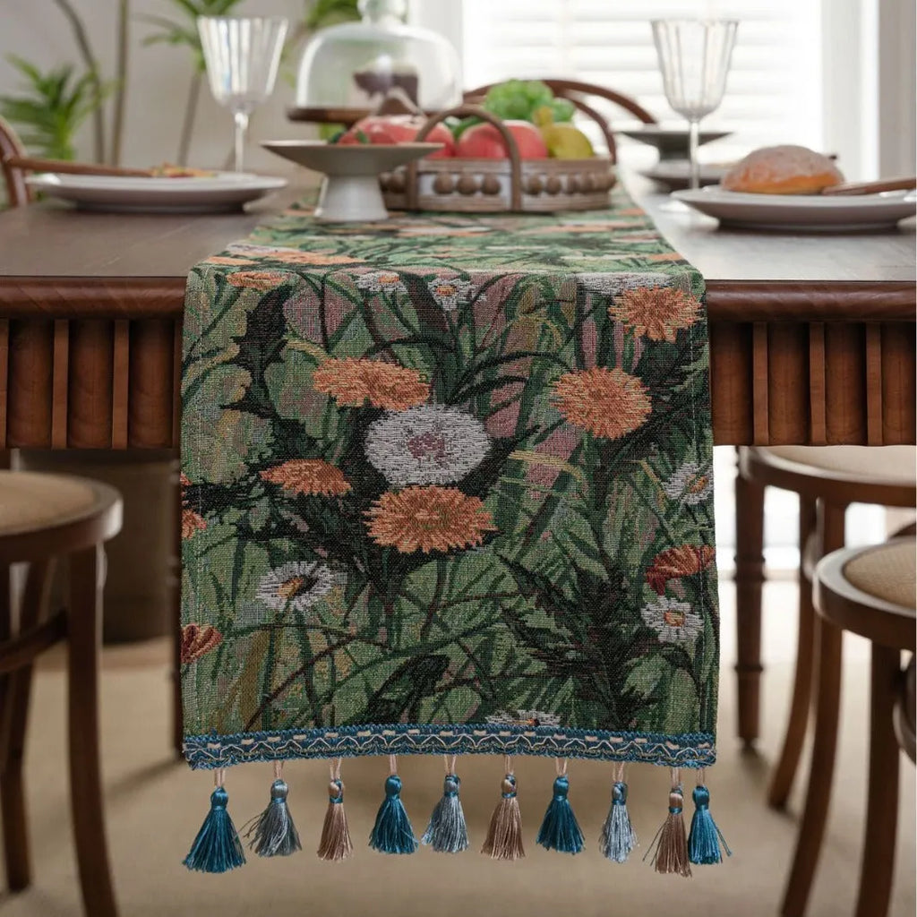 Beige jacquard table runner with floral pattern and long tassels draped over a wooden wedding table.