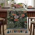 Beige jacquard table runner with floral pattern and long tassels draped over a wooden wedding table.