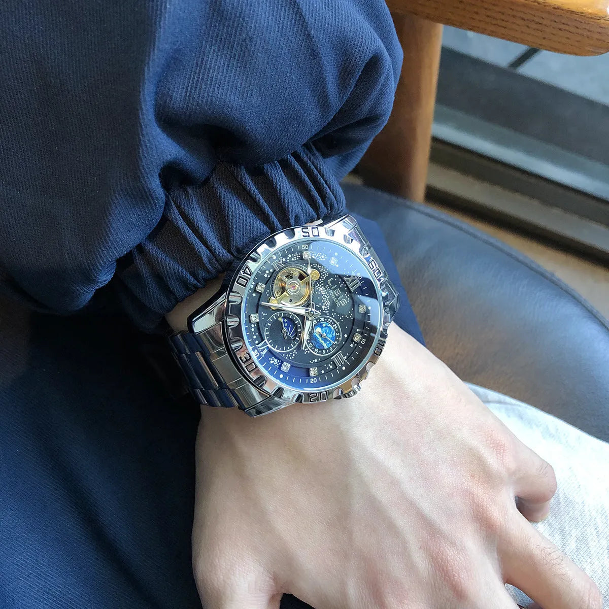 Silver case men's automatic watch with black dial, luminous hands, and brown leather strap.