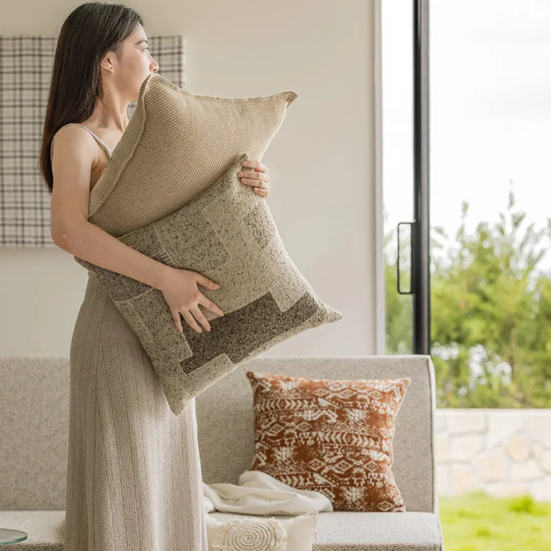 A square solid-colour cushion pillow on a sofa, showing its plain edge detail.