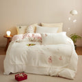 Winter milk fibre bedding four-piece set with green Christmas tree pattern on a bed.